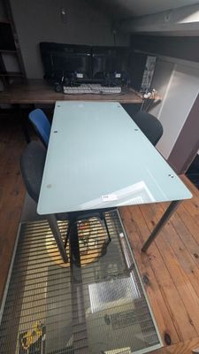 une table en verre avec un plateau en verre posée sur un parquet