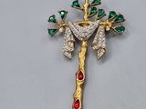 une image représentant une croix en or ornée de pierres vertes et rouges
