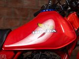 a close up of a red honda motorcycle parked in front of a brick wall