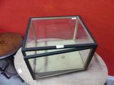 a glass box sitting on top of a table next to a small table
