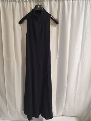 une robe noire suspendue à un cintre devant un rideau blanc