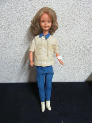 a doll with blonde hair and blue pants standing on a black surface