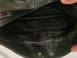 a person holding a black leather purse with one hand