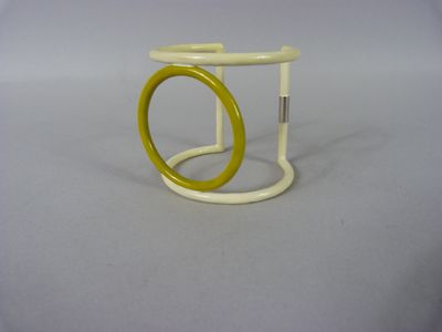 un anneau jaune et blanc posé sur un socle blanc