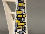 a white vase with a yellow and blue design on it