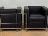 pair of black leather lounge chairs with chrome legs
