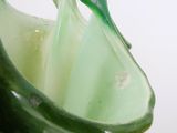 a glass vase with a green handle on a white table