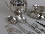 a silver tea set with a teapot, spoons, and utensils on a table