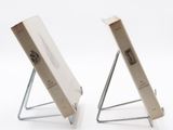 two books sitting on a metal stand on a white surface