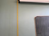 a blackboard hanging on the wall next to a measuring tape