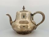 an antique silver teapot on a white surface with a white background