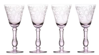quatre verres à vin sont alignés sur une surface blanche