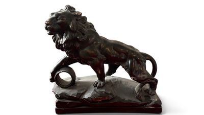 statue d'un lion perché sur un rocher, tenant une balle dans la gueule