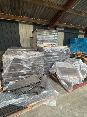 Plusieurs palettes de métal sont empilées les unes sur les autres dans un entrepôt.