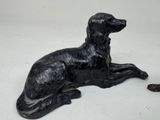 a statue of a dog laying down on the ground