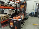 une borne d'arcade de basket-ball installée dans un garage, sur laquelle est posée un ballon de basket-ball
