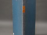 an old blue book sitting on top of a table next to a gray wall