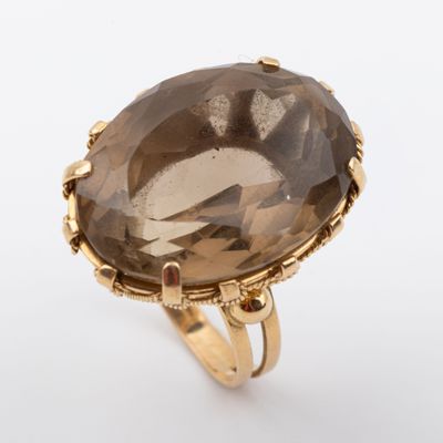 un gros plan d'une bague en or sertie d'un gros quartz fumé