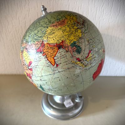 un petit globe terrestre posé sur un socle et sur lequel figure une carte