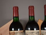 three bottles of red wine sit in a wooden crate