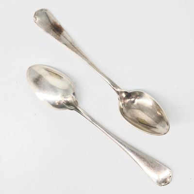 une paire de cuillères en argent posées sur une surface blanche