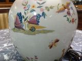 a white vase with flowers and butterflies on it sitting on a table