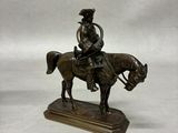 bronze figurine of a man on a horse on a white background