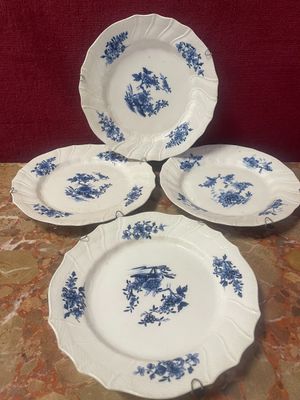 four blue and white plates with flowers on them on a table