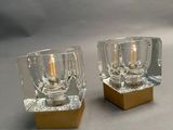 two glass candle holders with a gold base on a table