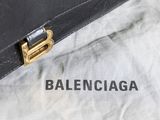 black leather briefcase sitting on top of a white sheet with the word balenciaga written on it