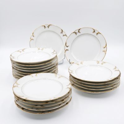 six assiettes plates blanches et dorées empilées les unes sur les autres