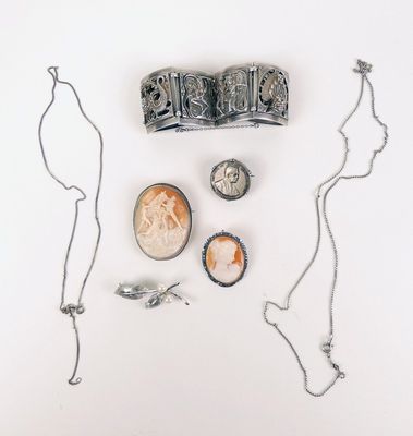 une photo représentant un collier, une pièce de monnaie et d'autres bijoux posés sur une surface blanche