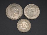 three silver coins sitting on top of each other on a black surface
