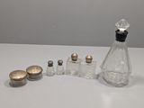 une petite bouteille en verre avec un bouchon argenté, à côté d'une autre petite bouteille en verre avec un bouchon argenté
