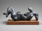 une sculpture représentant une femme allongée sur le dos sur un socle en bois