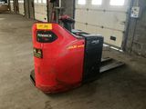 a red forklift in a warehouse with a door open