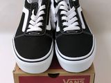 une paire de baskets Vans noires et blanches posées sur une boîte