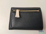 a small black wallet with a gold zipper on it