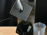 une cafetière posée sur une table, avec une tasse à côté