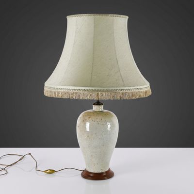 a white table lamp with a beige shade on top of it
