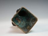 bronze sculpture of a square shaped object on a white surface