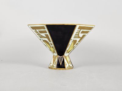 un gros plan d'un vase noir et doré posé sur une surface blanche