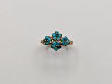 a gold and turquoise stone ring on a white surface