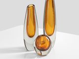 pair of orange glass vases sitting on top of a white surface