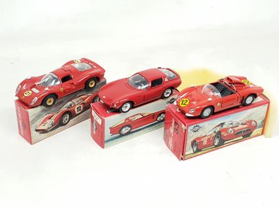 three red toy cars sitting on top of boxes on a white surface