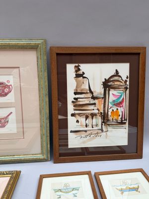 trois tableaux encadrés représentant différents types d'œuvres d'art, posés sur une table