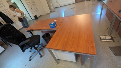 une femme debout au milieu d'une pièce où se trouvent un bureau et des chaises