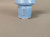 a small blue vase with a handle on a table