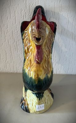 une figurine en céramique représentant un coq posée sur une table