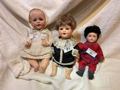 trois poupées assises côte à côte sur une couverture